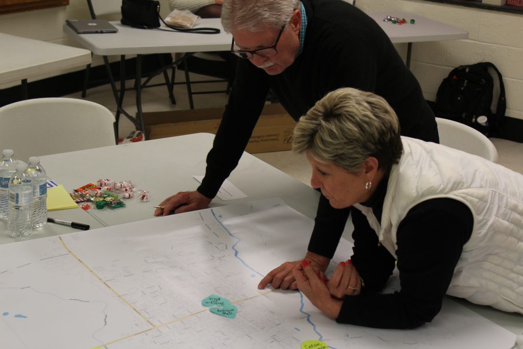 Strategic plan tasking force members lean over a table to examine documents.