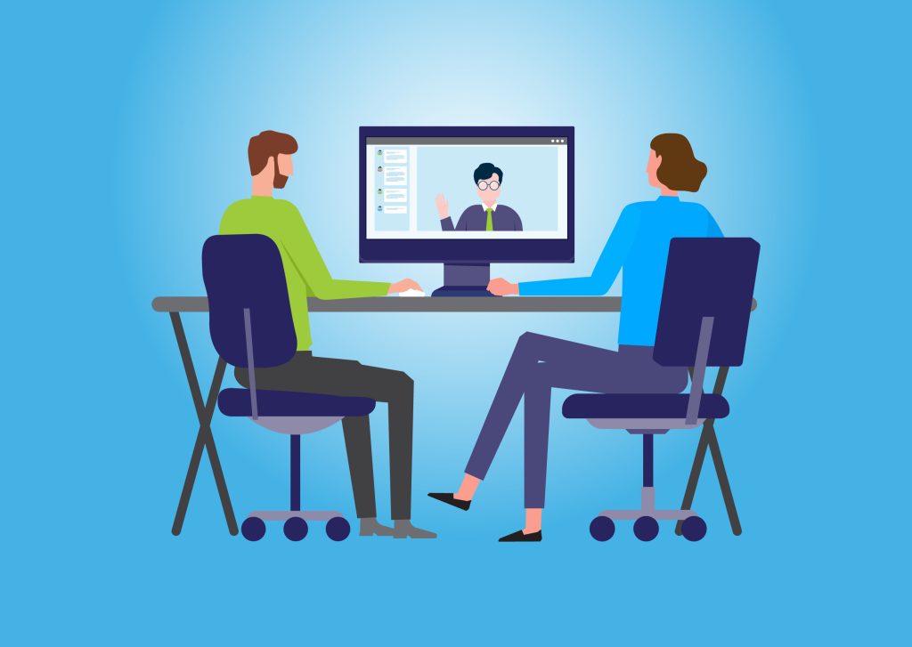 Two workers interact with someone on a large monitor, invoking scenes of a hybrid workspace.